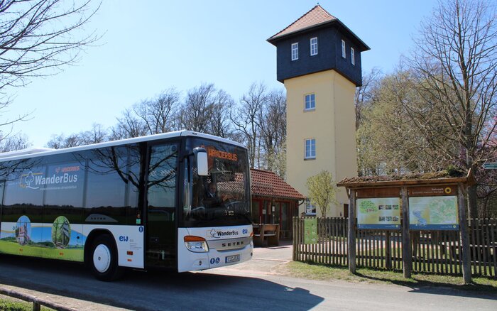 WanderBus vor gelbem Turmgebäude mit rotem Dach