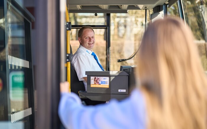 Person steigt in Bus ein, Fahrer vorne sichtbar