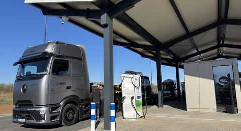 Ein grauer LKW parkt an einer Ladesäule. 