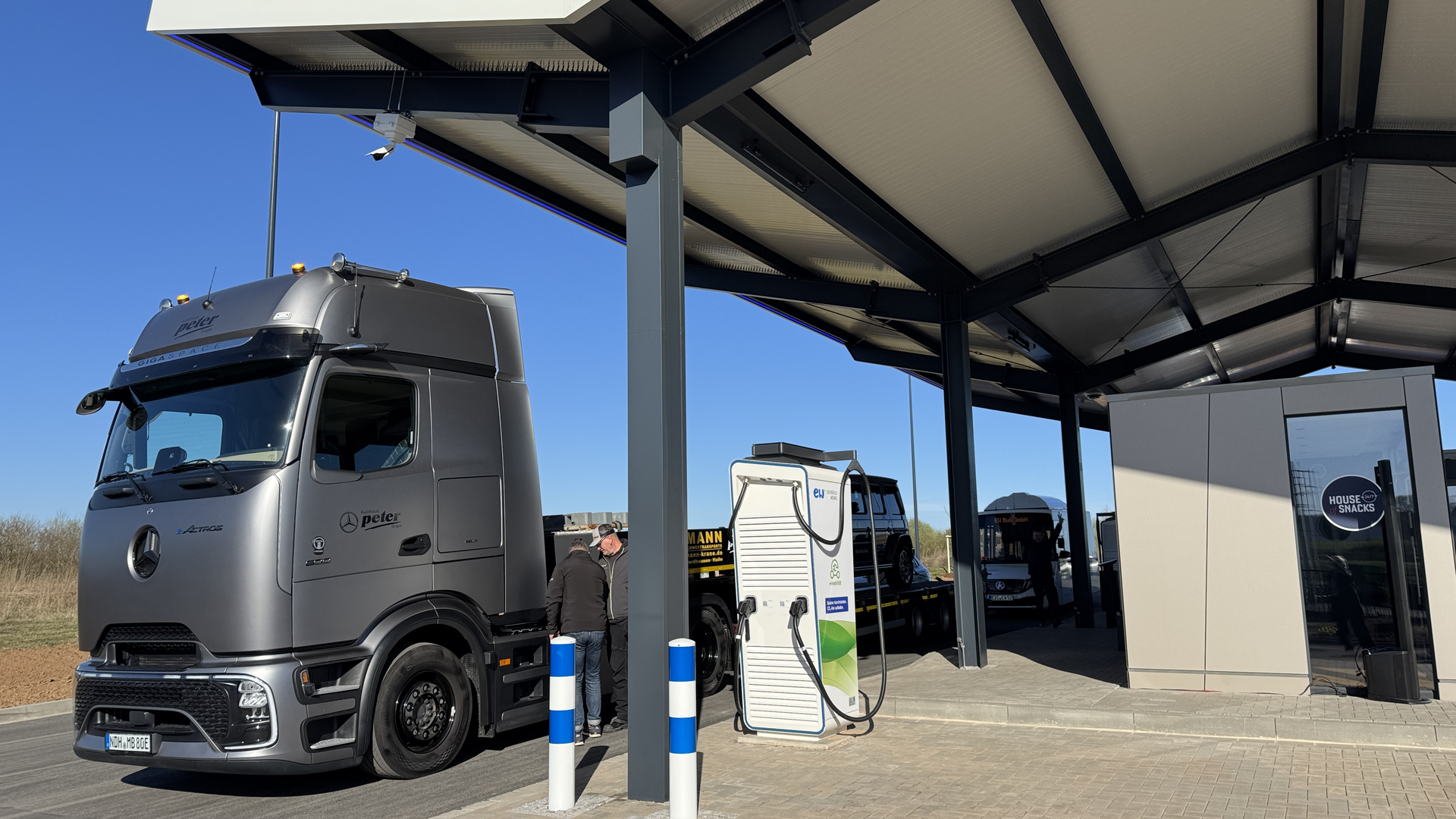 Ein grauer LKW parkt an einer Ladesäule. 