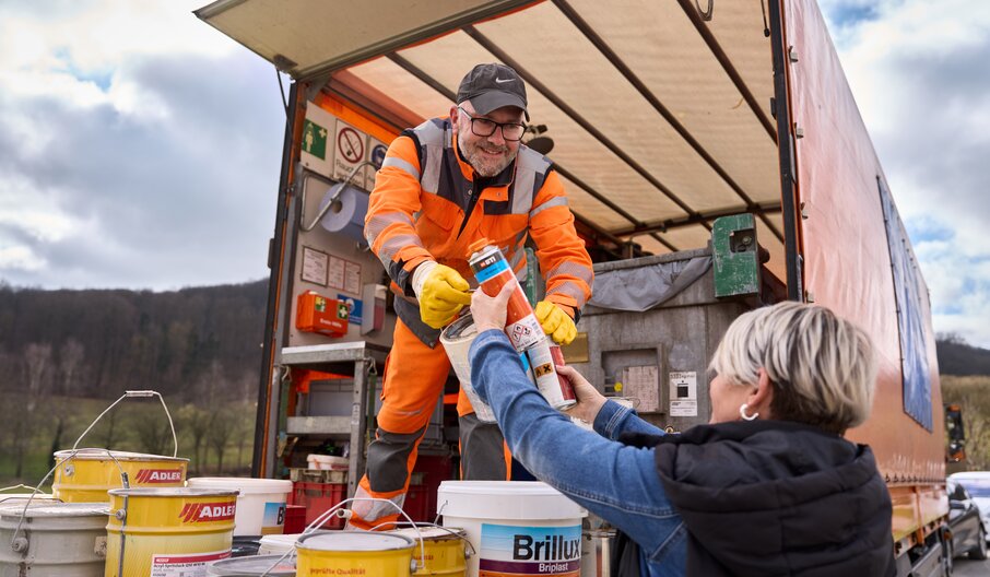 Kundin übergibt Dose mit Schadstoffen der Entsorgungskraft auf dem Schadstoffmobil