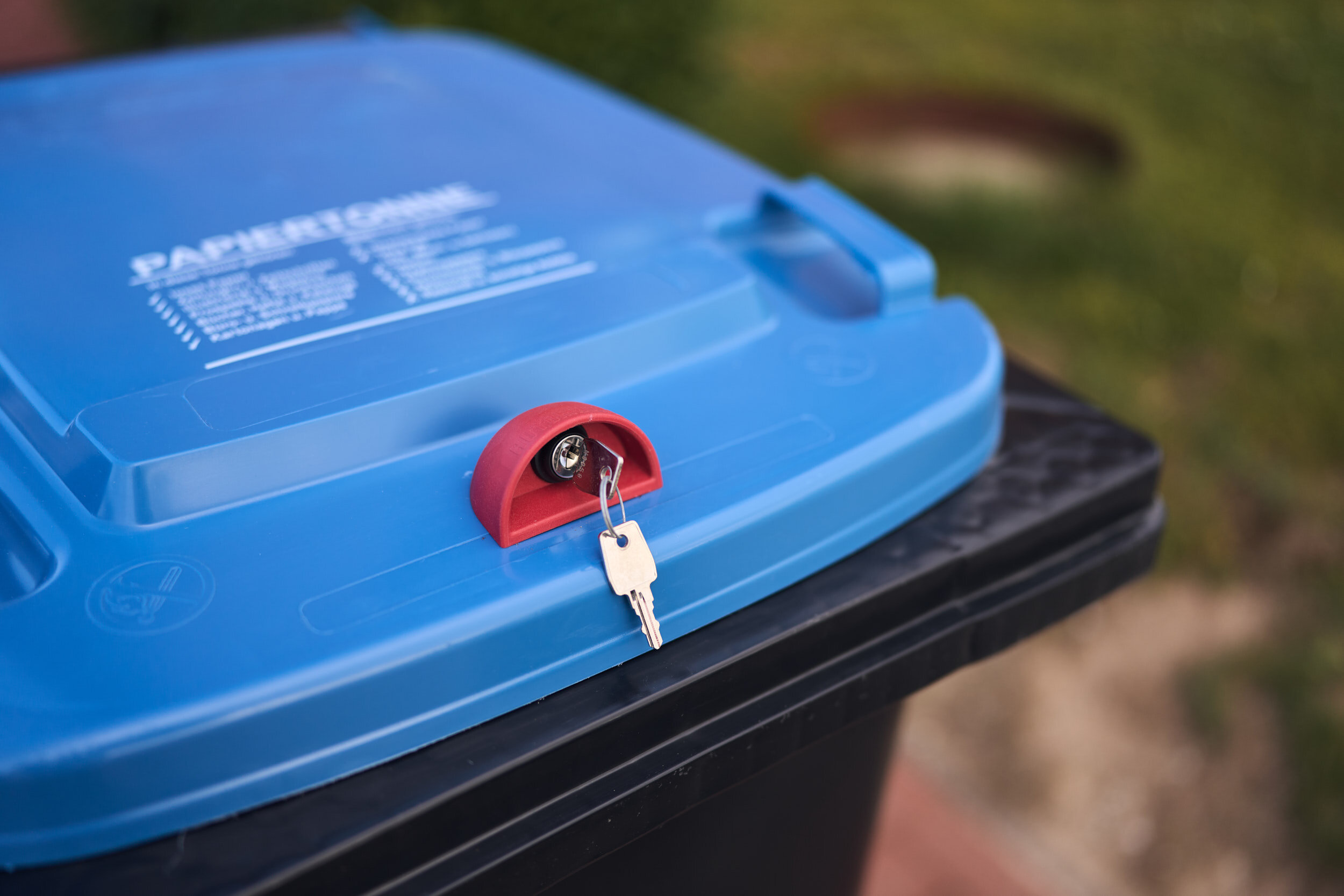 Eine Papiertonne mit Schloss und eingestecktem Schlüssel zum Abschließen