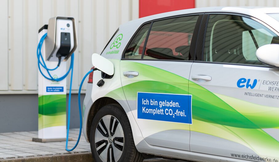 E-Auto an Ladesäule mit Aufschrift „Ich bin geladen. Komplett CO₂-frei.“